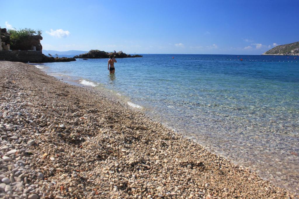 a person standing in the water on a rocky beach at Apartments and rooms by the sea Komiza, Vis - 2431 in Komiža