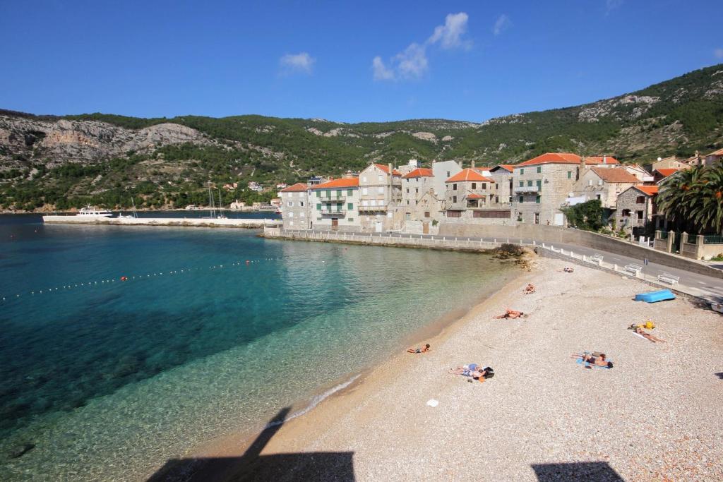 a beach with a group of people laying on the beach at Apartments and rooms by the sea Komiza, Vis - 2431 in Komiža