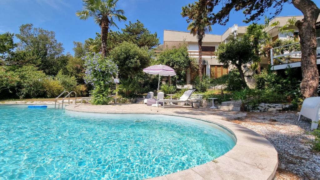 una piscina con sombrilla y sillas en un patio en Villa Duino Trieste Reception en Duino