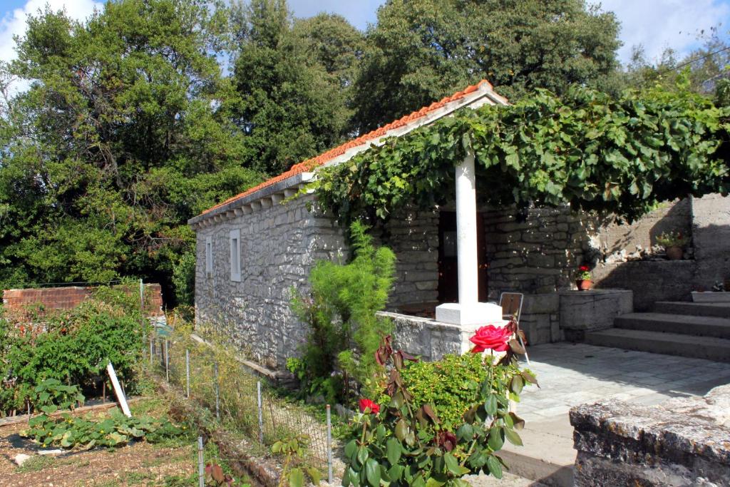 a garden with a stone building with roses at Holiday house with WiFi Zrnovo, Korcula - 4876 in Korčula