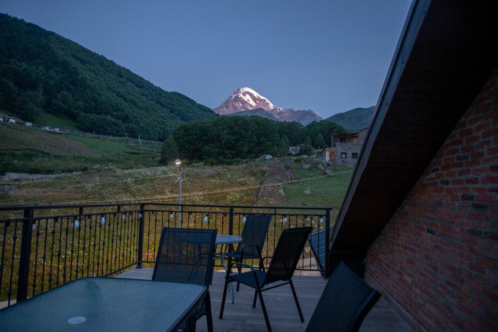 a balcony with a table and chairs and a mountain at Hotel GENI Kazbegi in Stepantsminda