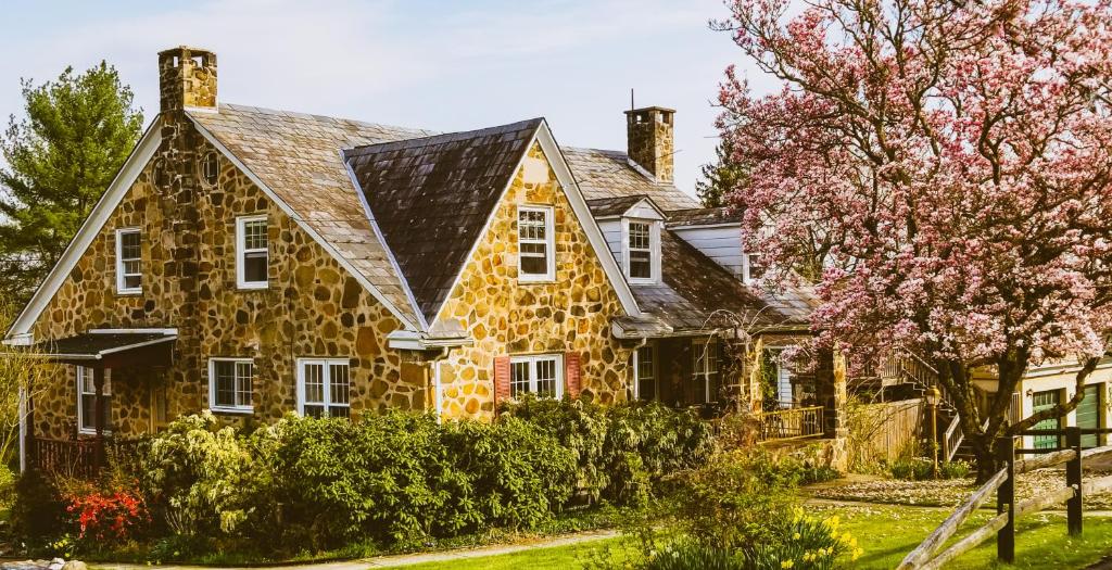 a stone house with a black roof at Victorian Apt at SanctuaryoftheSwan dog friendlyhotel alternative farm stay in Birdsboro