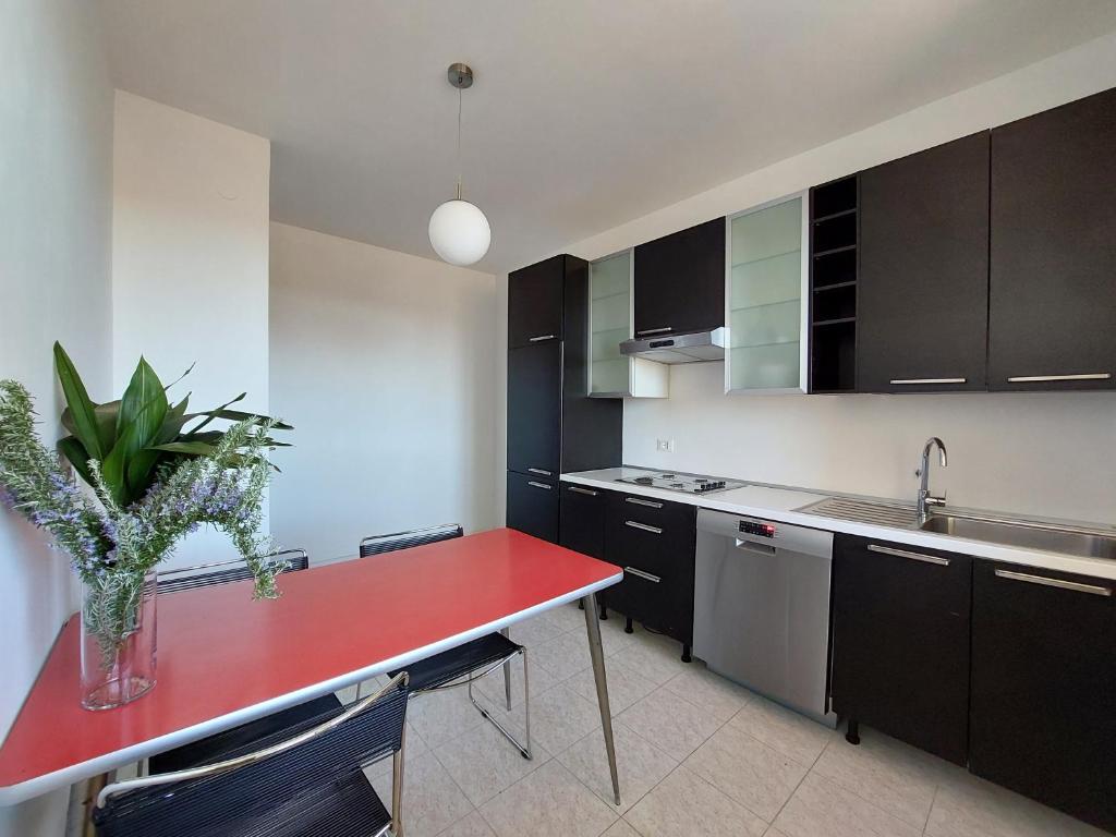una cocina con una mesa roja con un jarrón. en Appartamento Codroipo Centrale, en Codroipo