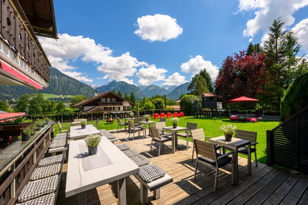 eine Terrasse mit Tischen, Stühlen und Bergen im Hintergrund in der Unterkunft Hotel Tannhof in Oberstdorf