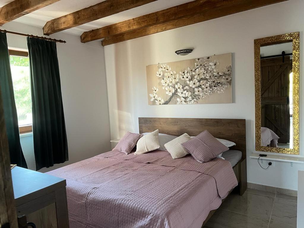 una camera da letto con un letto con lenzuola viola e uno specchio di Vikendica Oliver a Medovdolac