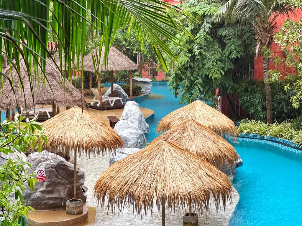 ein Resort mit einem Pool mit Strohschirmen in der Unterkunft Seven Seas Condo Resort Jomtien Pattaya #Pool View #Near Beach in Jomtien Beach