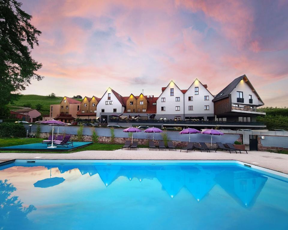 einen Pool mit Stühlen und Sonnenschirmen vor einem Resort in der Unterkunft Best Western Hotel & SPA Le Schoenenbourg in Riquewihr