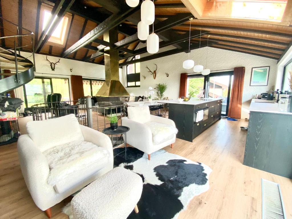 a living room with two white chairs and a kitchen at Beautiful Chalet on the piste in Swiss Alps in Alt Sankt Johann