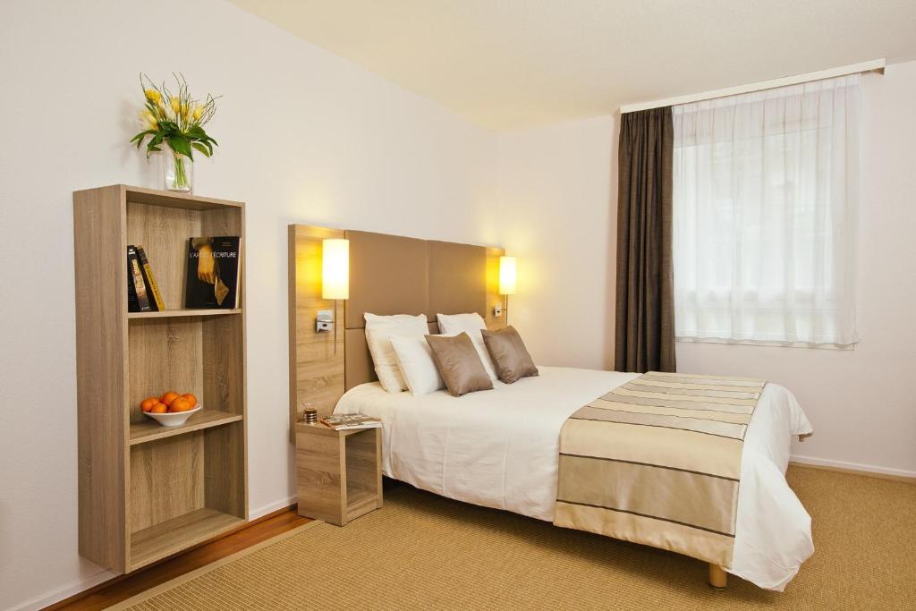 a hotel room with a large bed and a window at Séjours & Affaires Strasbourg Kleber in Strasbourg