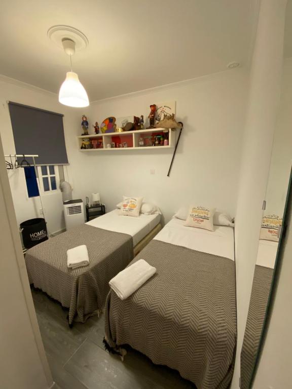 a small room with two beds and a shelf at Habitaciones la viña in Cádiz