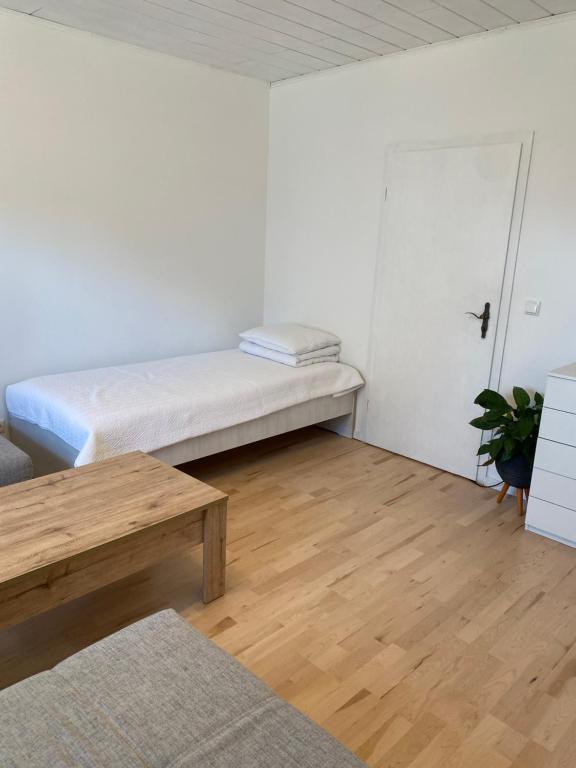 a white room with a bed and a wooden floor at Ferienwohnung Diana und Manuel in Weinheim