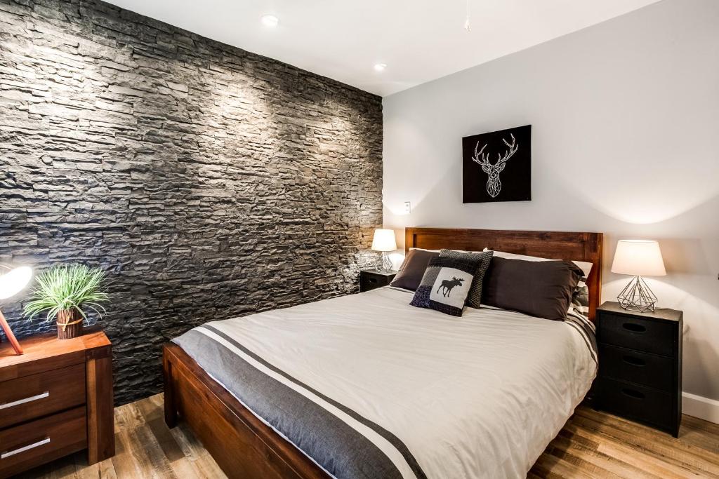 um quarto com uma cama e uma parede de pedra em Le Villageois by Gestion ELITE em Mont-Tremblant