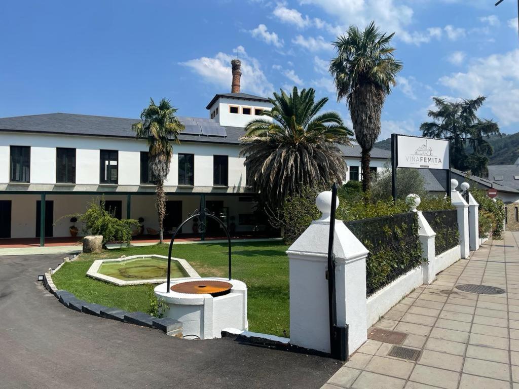 un bâtiment blanc avec des palmiers devant lui dans l'établissement Viña Femita, à Villafranca del Bierzo