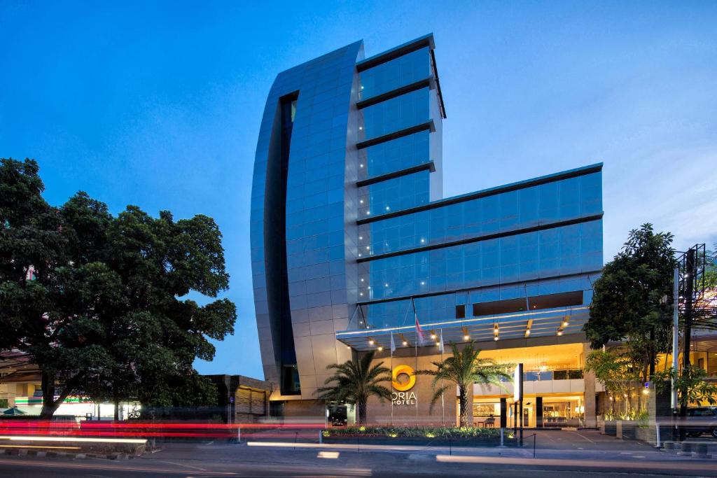 a tall glass building with a street in front of it at Oria Hotel Jakarta in Jakarta