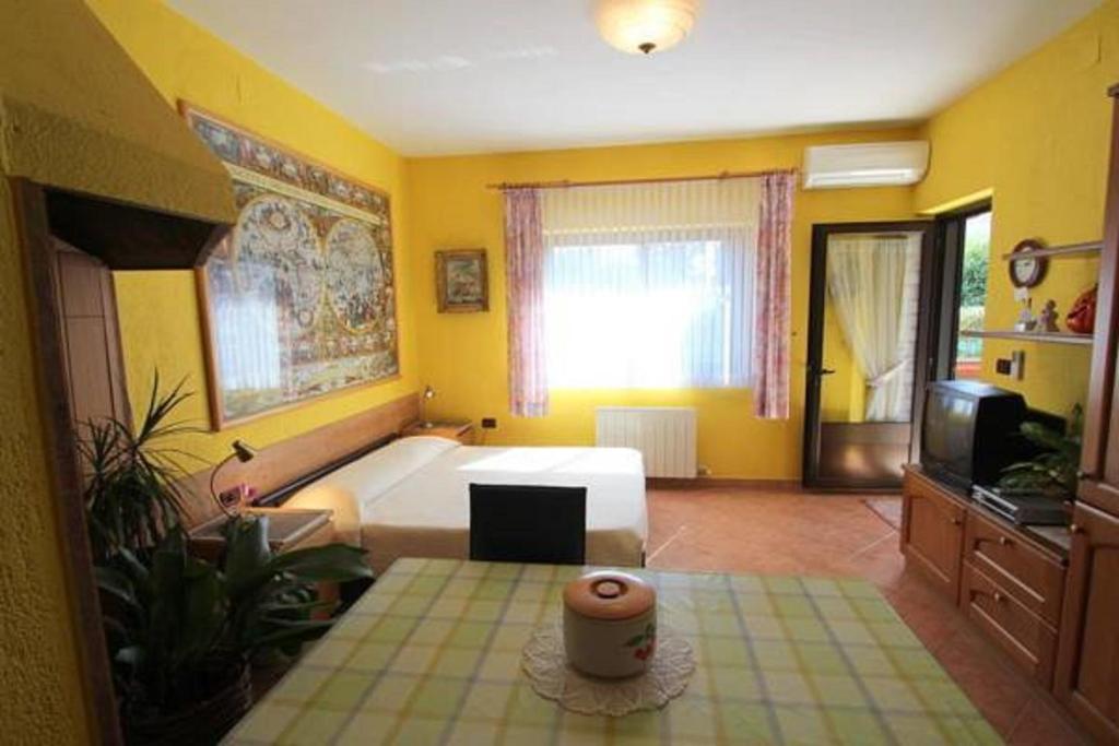ein gelbes Schlafzimmer mit einem Bett und einem TV in der Unterkunft Apartments Daniela in Novigrad Istria