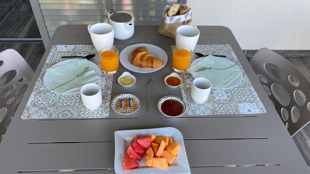 a table with two plates of food and orange juice at LES ROCHES DE BAUDISSET in Saint-Paul-en-Forêt