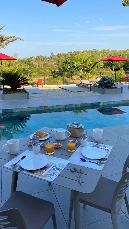 a table with food on it next to a swimming pool at LES ROCHES DE BAUDISSET in Saint-Paul-en-Forêt