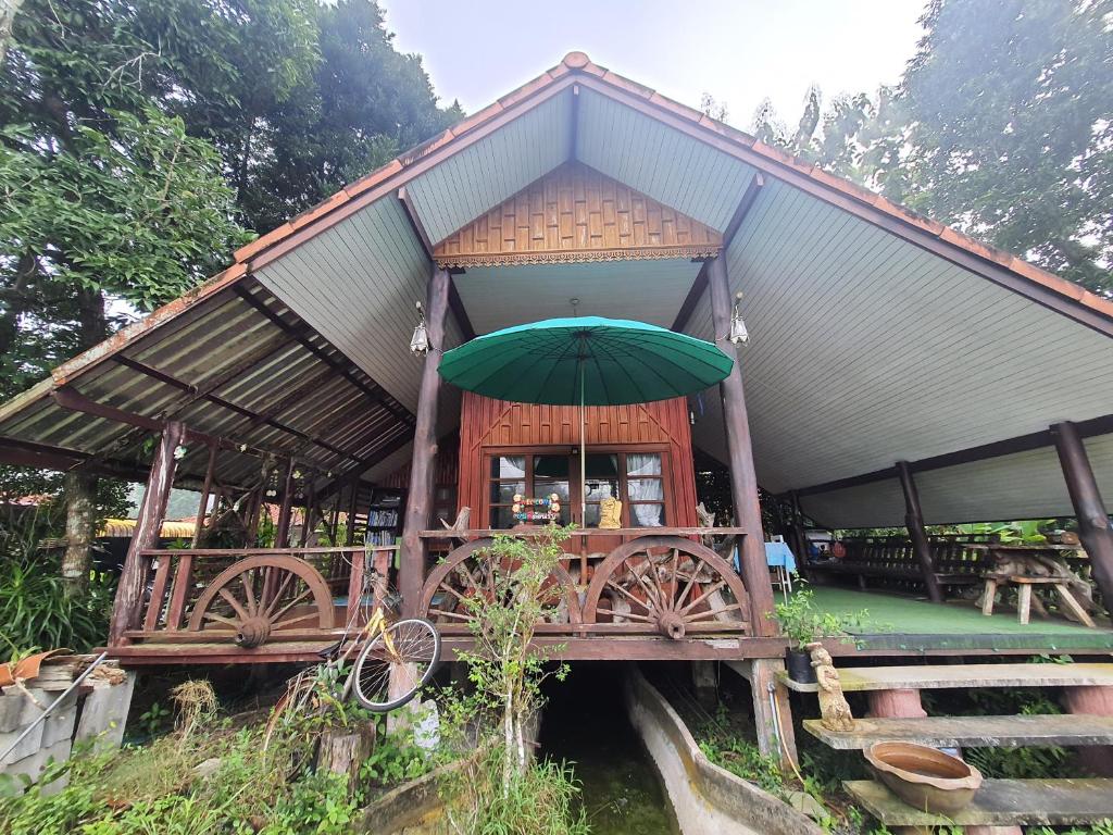 Ban Pak NamにあるBaan Thabthong Homestay (บ้านทับทอง โฮมสเตย์)の橋の上に緑の傘を持つ建物