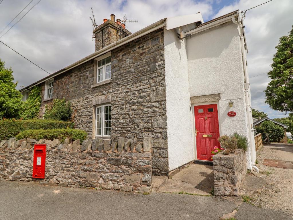 una vieja casa de piedra con una puerta roja en The Old Post Office en Colwyn Bay