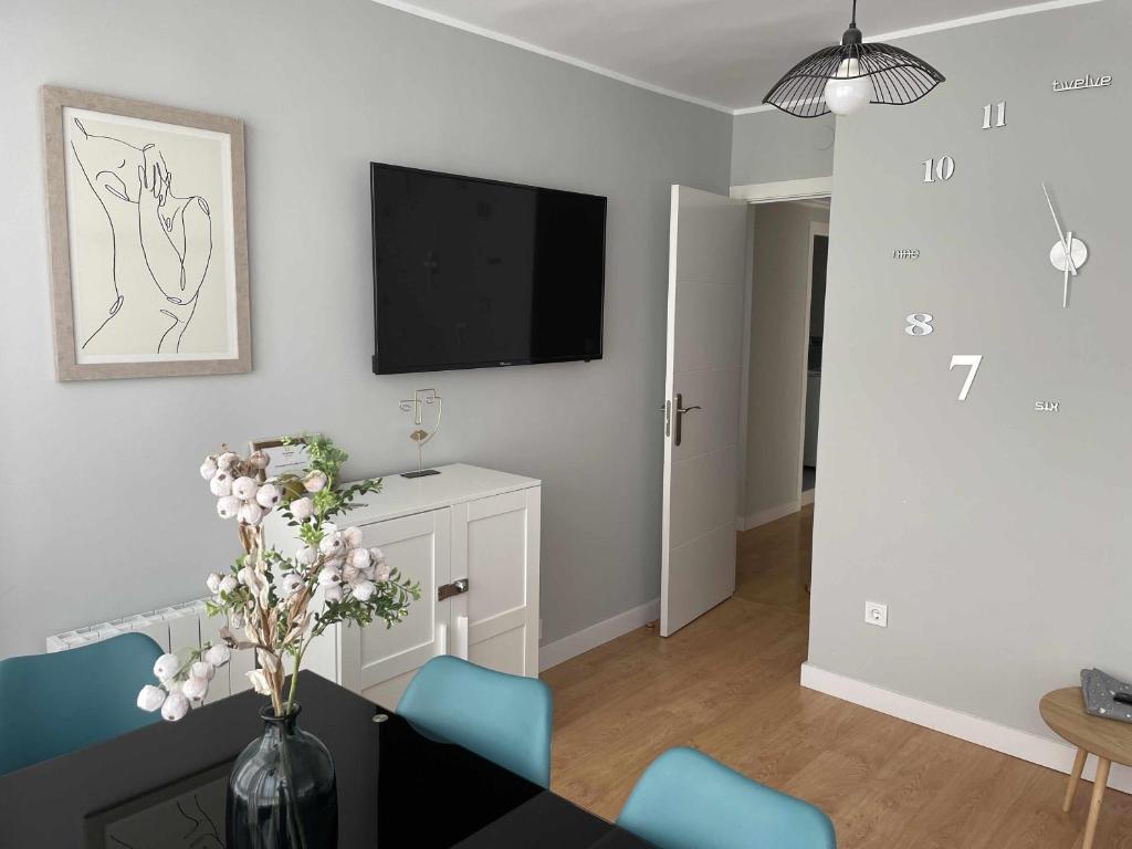 ein Wohnzimmer mit einem Tisch und einem TV an der Wand in der Unterkunft Arena Playa Gijón by Flowhome in Gijón