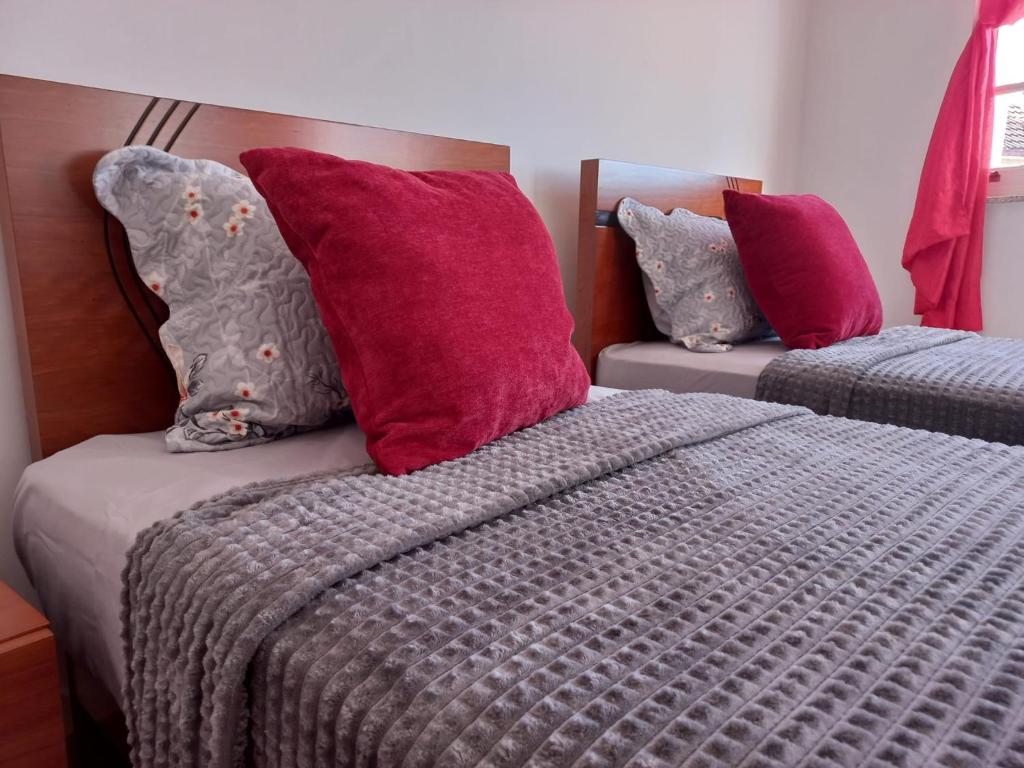 sypialnia z 2 łóżkami z czerwonymi i fioletowymi poduszkami w obiekcie Studios Rossio w mieście Viseu