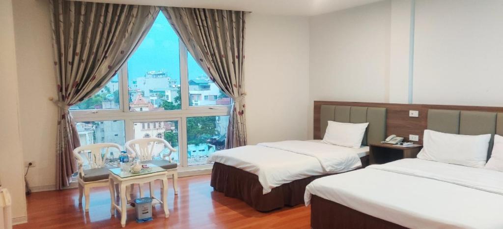 a hotel room with two beds and a large window at Khách sạn Phúc Thành in Hanoi