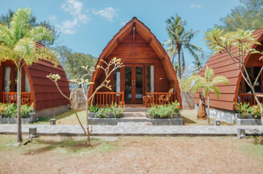 ein Haus mit einem Holzhaus mit Palmen in der Unterkunft Laba Laba Bungalow in Gili Meno