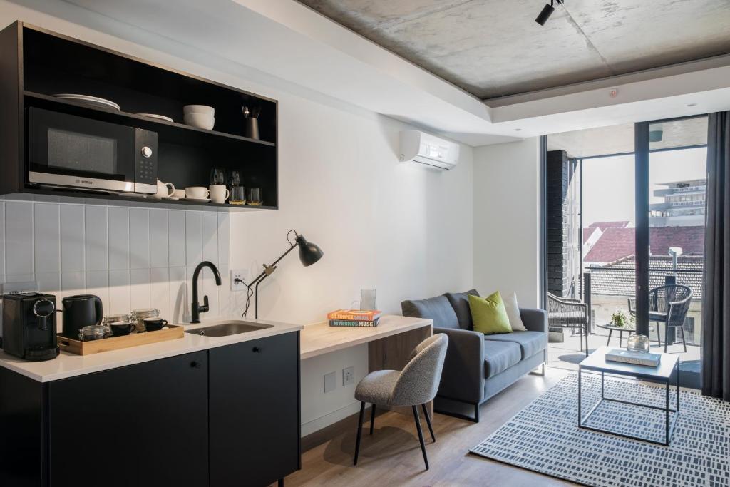 a kitchen and living room with a couch and a table at Home Suite Hotels Station House in Cape Town