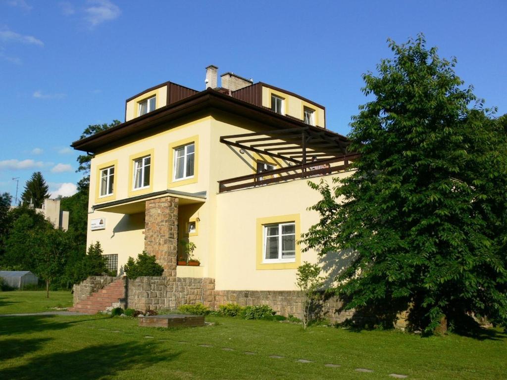 ein großes gelbes Haus mit Dach in der Unterkunft Penzion Továrníkova vila in Skuhrov nad Bělou