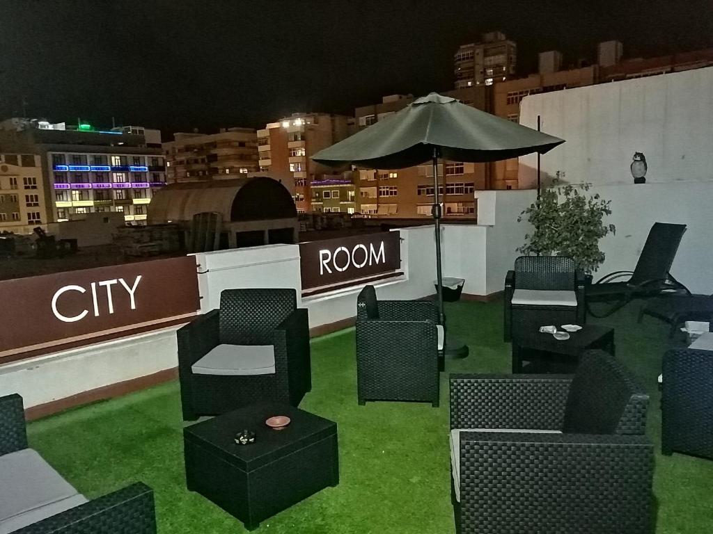 een groep stoelen en een paraplu op een dak bij City Room Las Palmas in Las Palmas de Gran Canaria