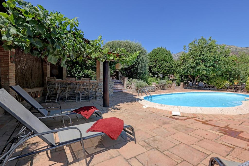 uma piscina com cadeiras e uma toalha vermelha ao lado em Finca del Rio em Cañada del Real Tesoro