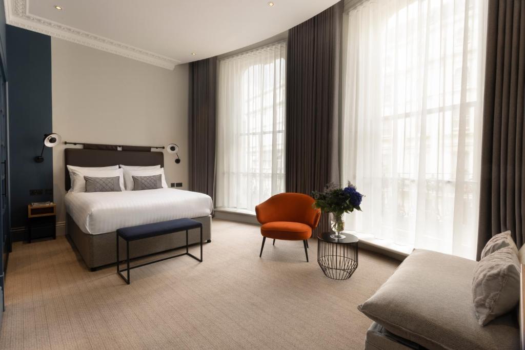 - une chambre avec un lit, une chaise et un canapé dans l'établissement 55 by Le Mirage, à Londres