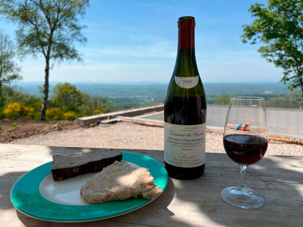 a bottle of wine and a plate of food and a glass at Bienvenue au Mas du Roulier, villa provençale avec vue hypnotique sur la chaine des Puys in Thiers