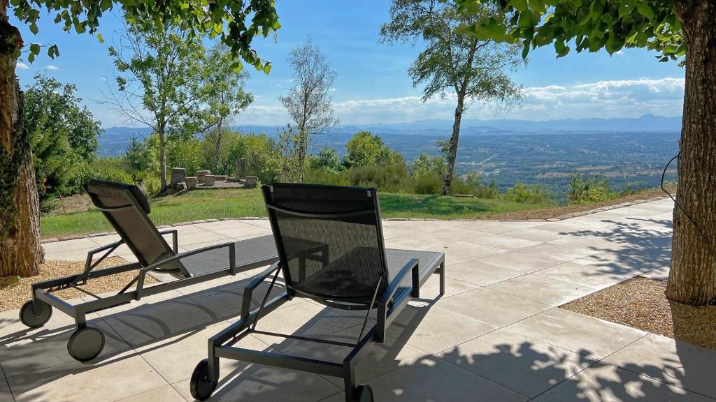 two chairs and a table on a patio with a view at Bienvenue au Mas du Roulier, villa provençale avec vue hypnotique sur la chaine des Puys in Thiers