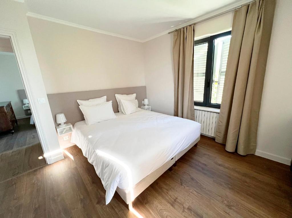 a white bed in a room with a large window at Bienvenue au Mas du Roulier, villa provençale avec vue hypnotique sur la chaine des Puys in Thiers