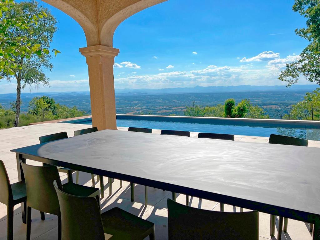 a table and chairs on a balcony with a view at Bienvenue au Mas du Roulier, villa provençale avec vue hypnotique sur la chaine des Puys in Thiers