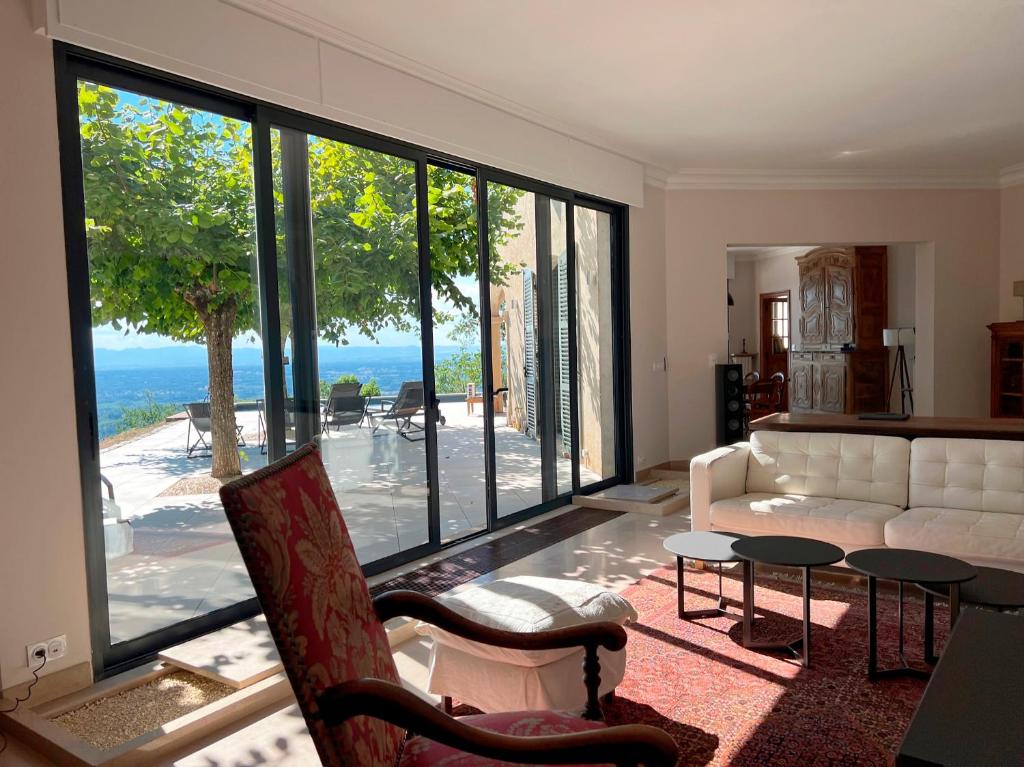 a living room with a couch and a large window at Bienvenue au Mas du Roulier, villa provençale avec vue hypnotique sur la chaine des Puys in Thiers
