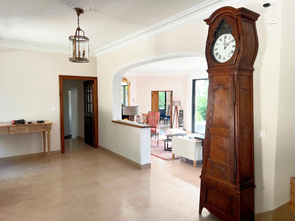 a large wooden grandfather clock in a living room at Bienvenue au Mas du Roulier, villa provençale avec vue hypnotique sur la chaine des Puys in Thiers