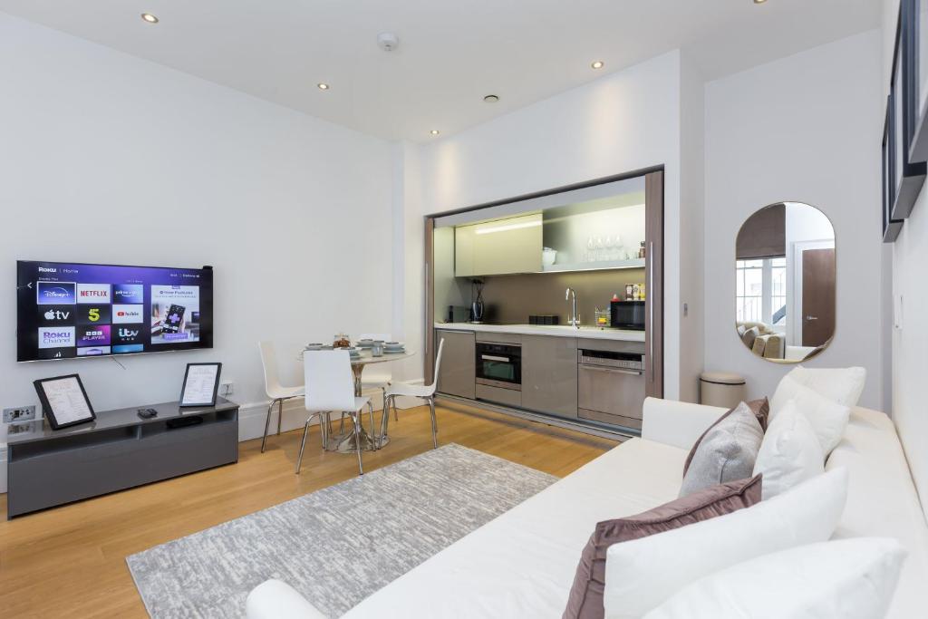 a living room with a white couch and a kitchen at The Dorset Suite - Stylish New 1 Bedroom Apartment In Marylebone in London