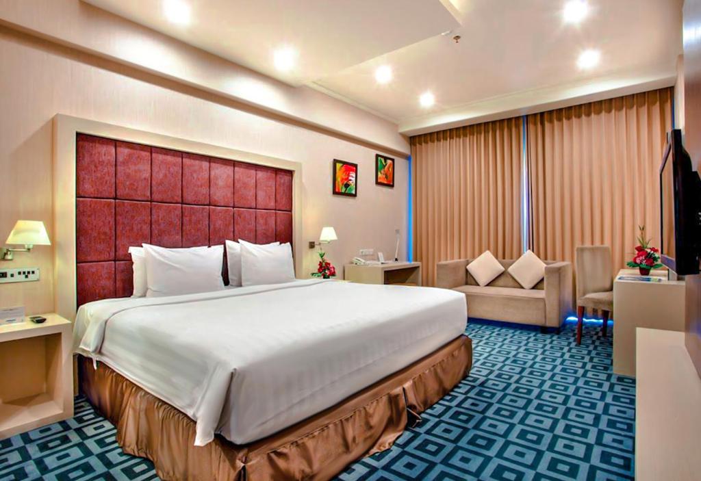a hotel room with a large bed and a couch at Surabaya Suites Hotel Powered by Archipelago in Surabaya
