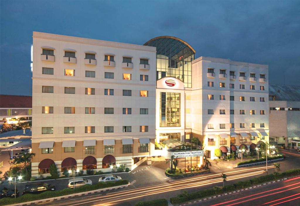 a large white building with cars parked in front of it at Surabaya Suites Hotel Powered by Archipelago in Surabaya