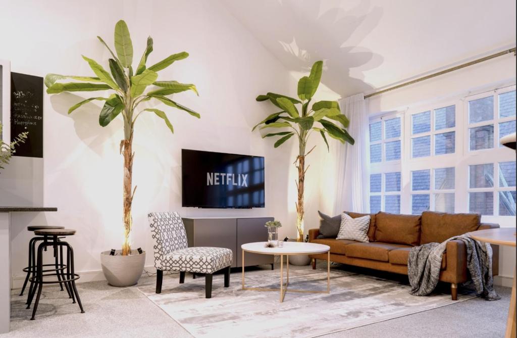 a living room with a couch and two palm trees at Luxury Apartment In The Heart of Leicester With Parking in Leicester