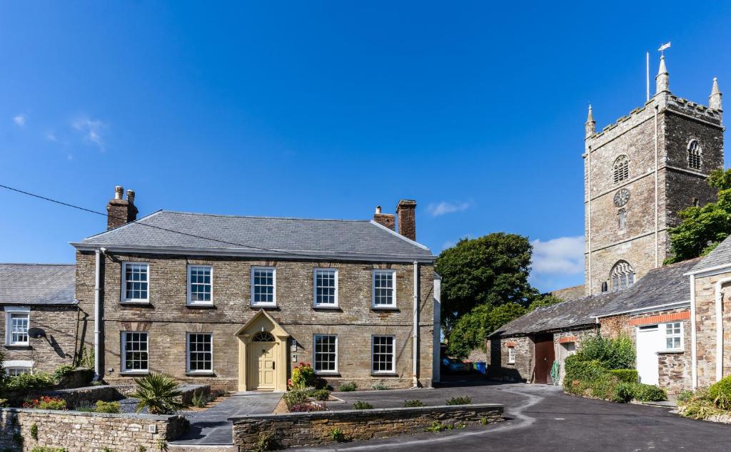 an old stone building with a church in the background at Finest Retreats - The Half-ARC of Padstow in St. Issey