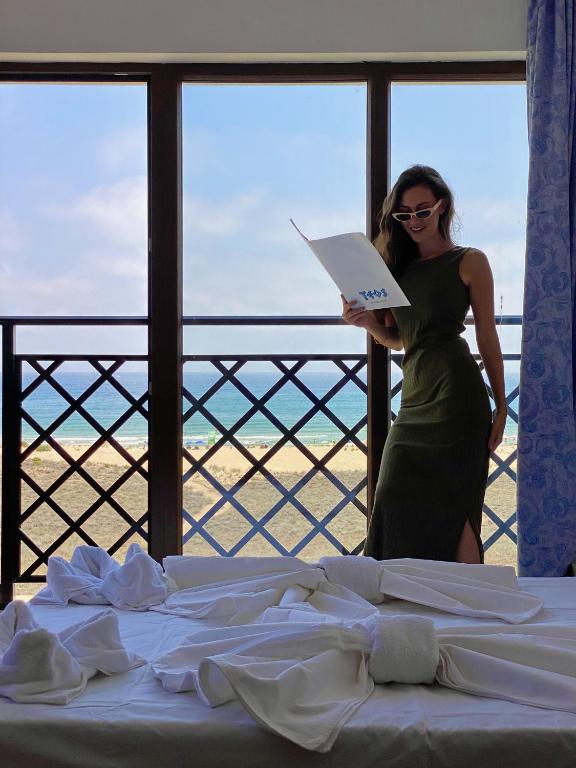 a woman standing next to a bed in a room at Teos Apartments Primorsko in Primorsko