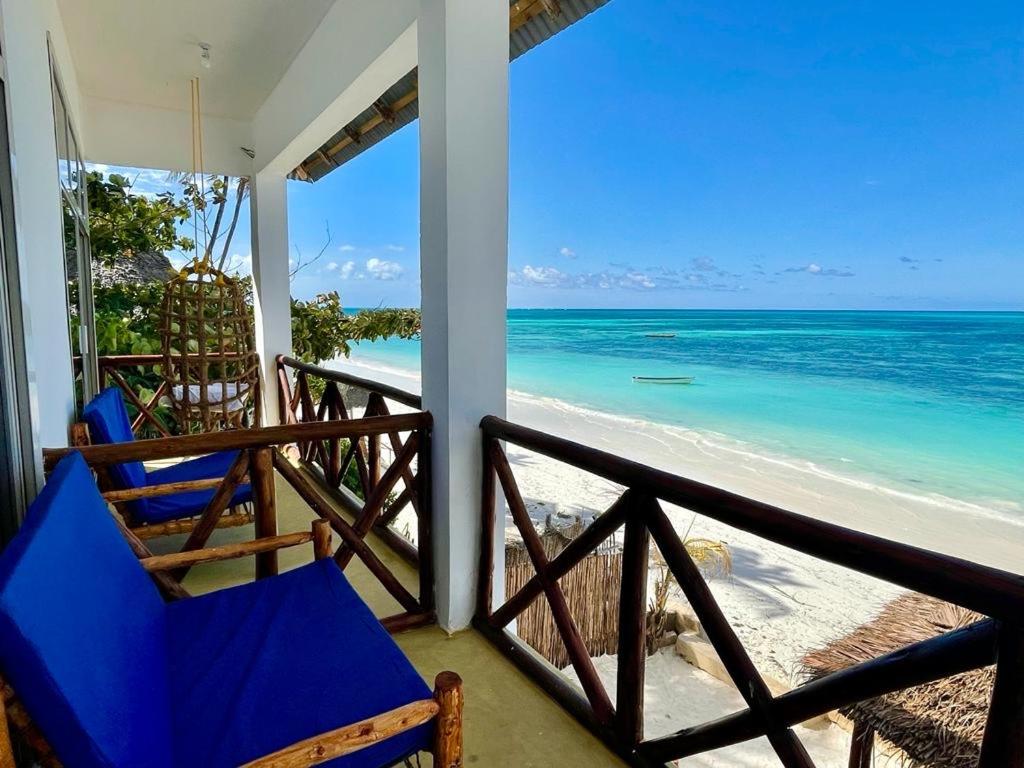 a porch with two chairs and the beach at Equalia Rose hotel in Jambiani