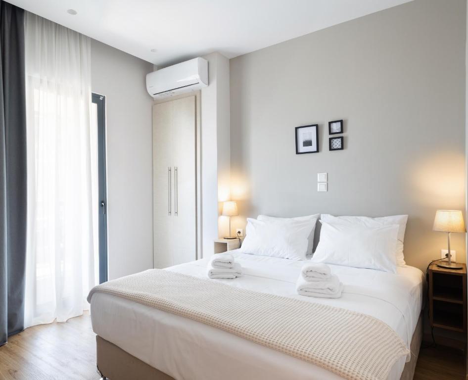 a white bedroom with a large bed with two towels on it at Mood Athens Luxury Apartments and Suites in Athens