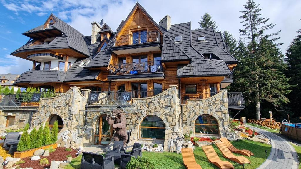 a large house with a statue in front of it at Aparthotel Delta Royal in Kościelisko