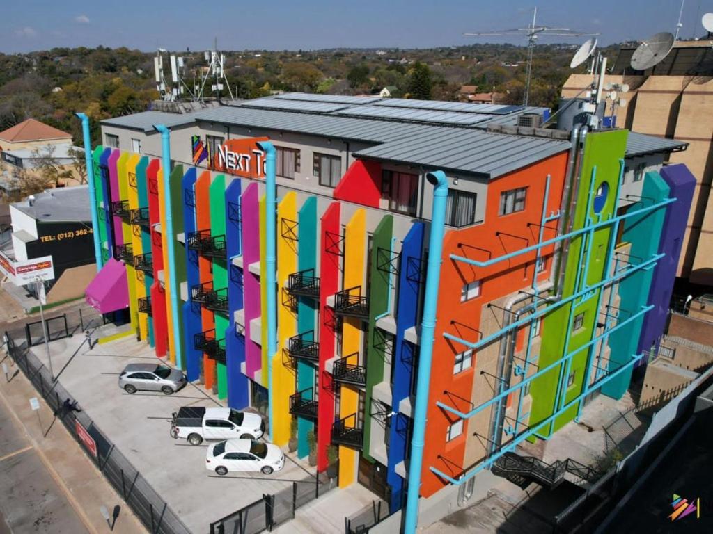 un edificio colorato con auto parcheggiate di fronte di Next To Apartment Hotel a Pretoria