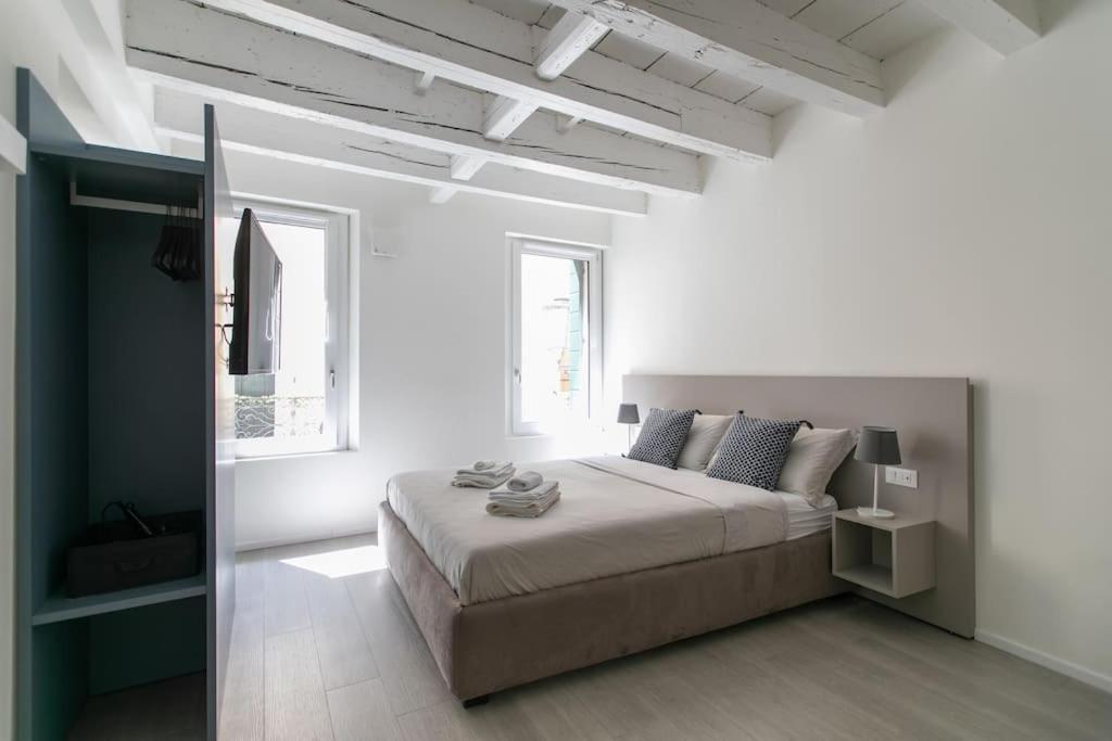 a white bedroom with a bed and a window at Residenza SubitoSanto - Appartamento 2A "Angelina" in Padova