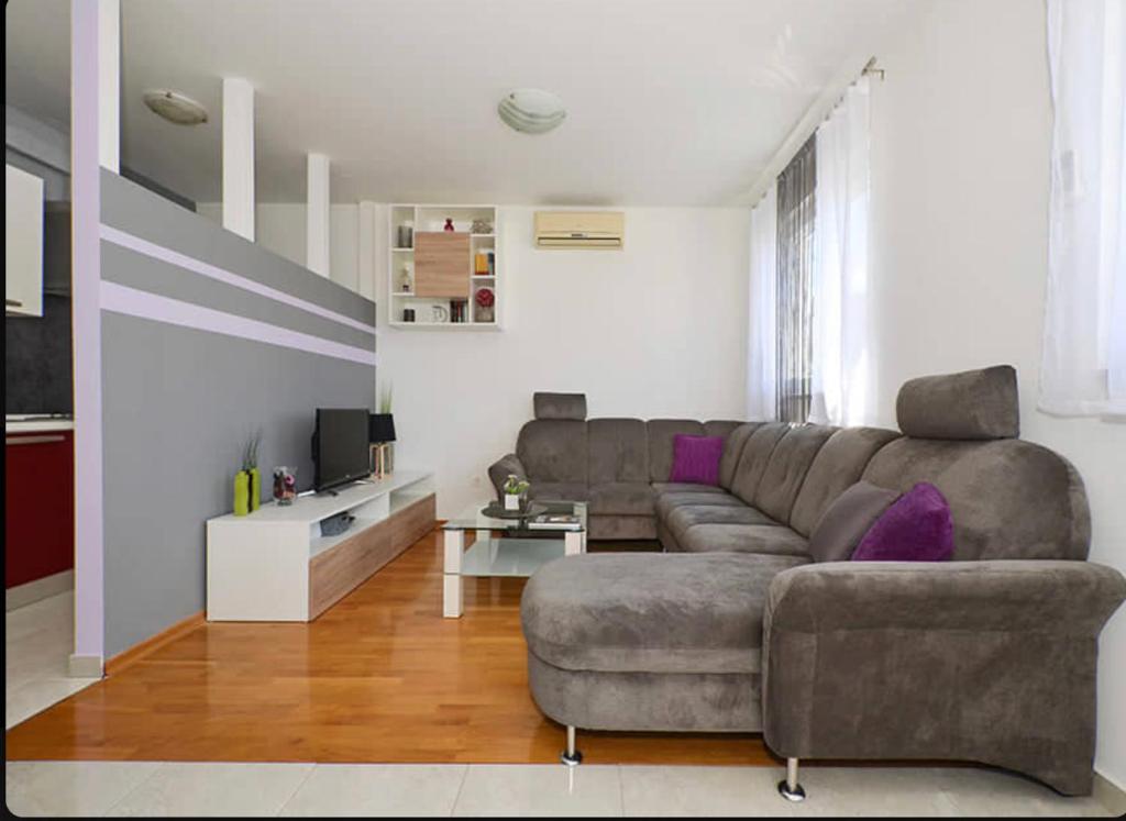 a living room with a gray couch and purple pillows at Apartment Charlie in Podstrana